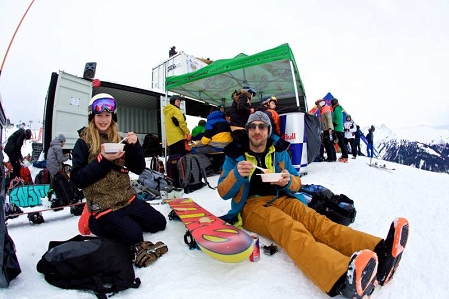 2 Menschen sitzen im Schnee und essen Gulasch